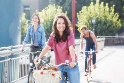 drei Menschen fahren mit dem Rad über eine Brücke