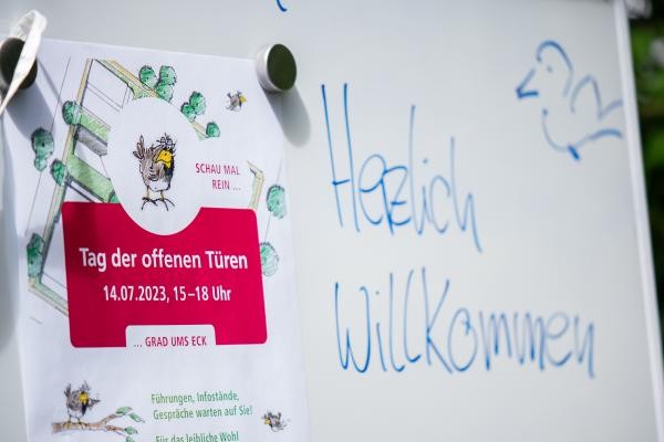 Auf einem Whiteboard steht neben dem Flyer vom Tag der offenen Tür: "Herzlich Willkommen"