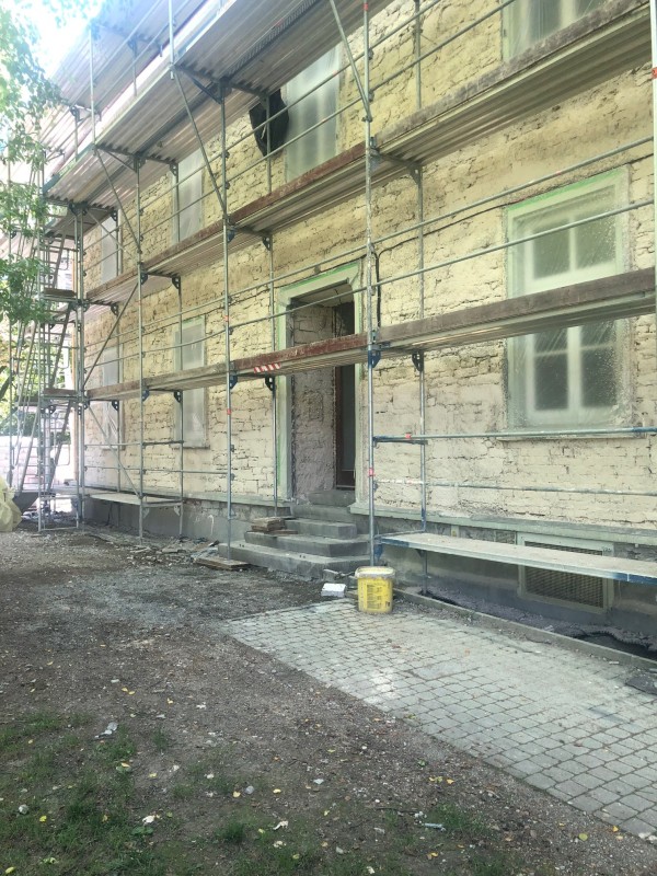 Fassade mit Haupteingang und Gerüst, Mauerwerk für Dämmputz vorbereitet
