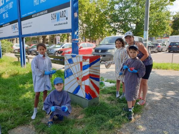 Schülerinnen und Schüler bemalen einen Verteilerkasten.