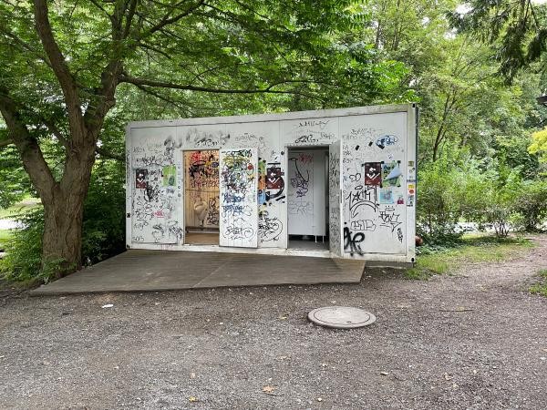 Mit Graffiti beschmierter Toiletten-Container in einem Park
