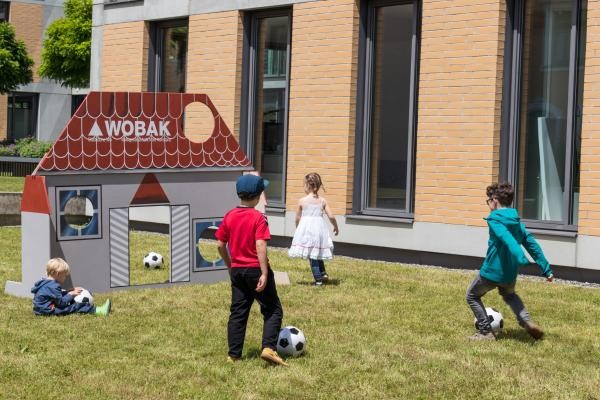 Kinder kicken Fußbälle auf eine hausförmige Torwand