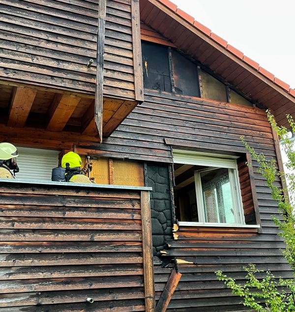 Feuerwehrmänner auf Balkon, Haus mit Holzfassade
