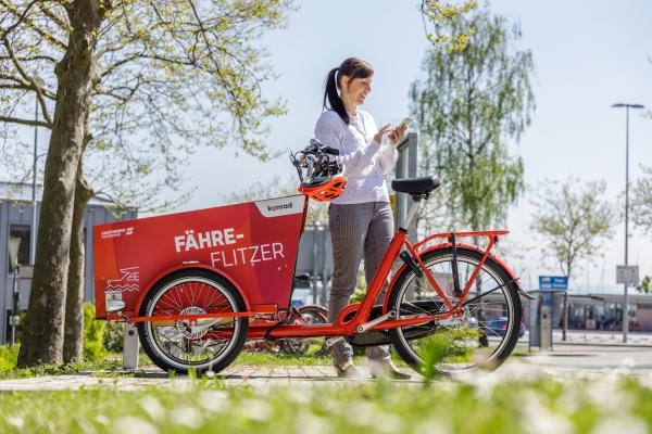 Eine Frau mietet ein Lastenrad des Fahrradmietsystems konrad.