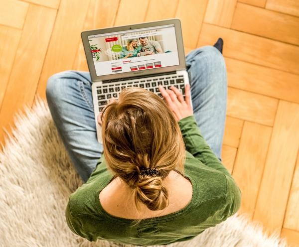 Ein Frau sitzt am Boden und bedient einen Laptop.
