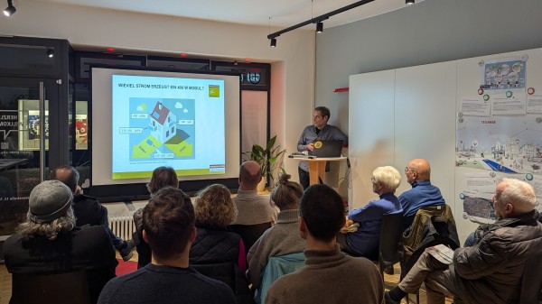 Eine Person hält einen Vortrag mit einer Präsentation vor einem Publikum