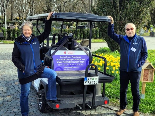 Caddy Fahrzeug und zwei Personen, die daneben stehen