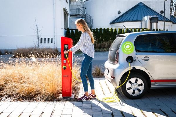 Eine Frau lädt ihr E-Auto an einer Stromladesäule